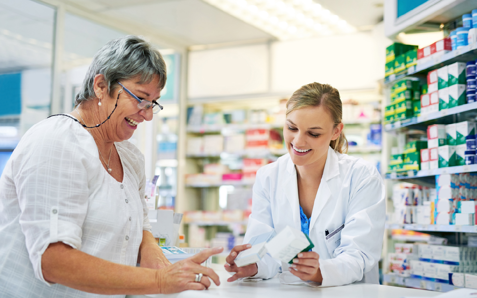 Pharmacist explaining prescription medication to woman in the pharmacy for pharmaceutical healthcare treatment