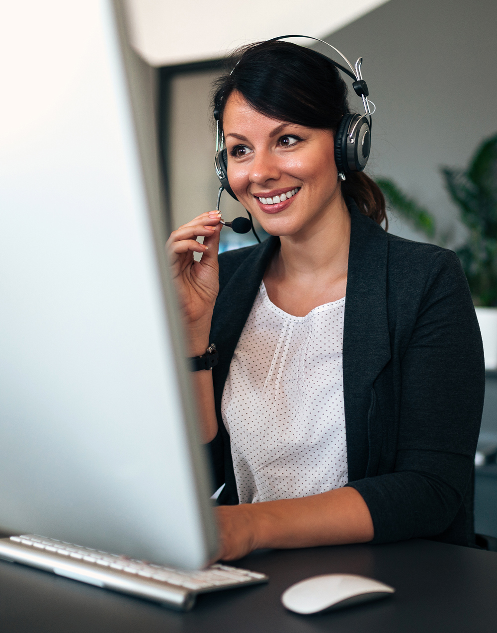Female talking with earphone reviewing her computer screen
