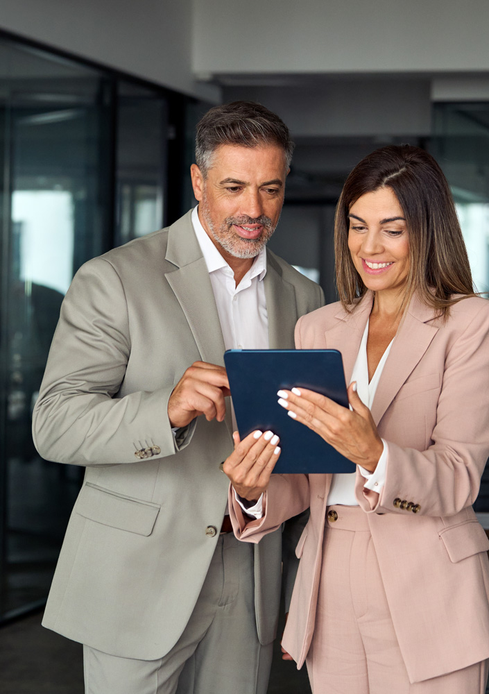 corporate business executives man and woman wearing suits holding tablet tech device having discussion working