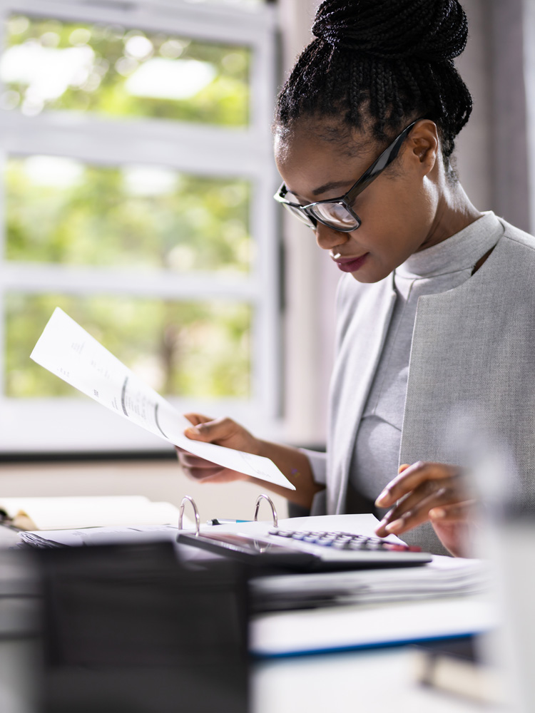 woman holding a bill and running numbers on a calculator