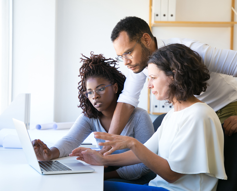 employees working together to solve a problem on a computer