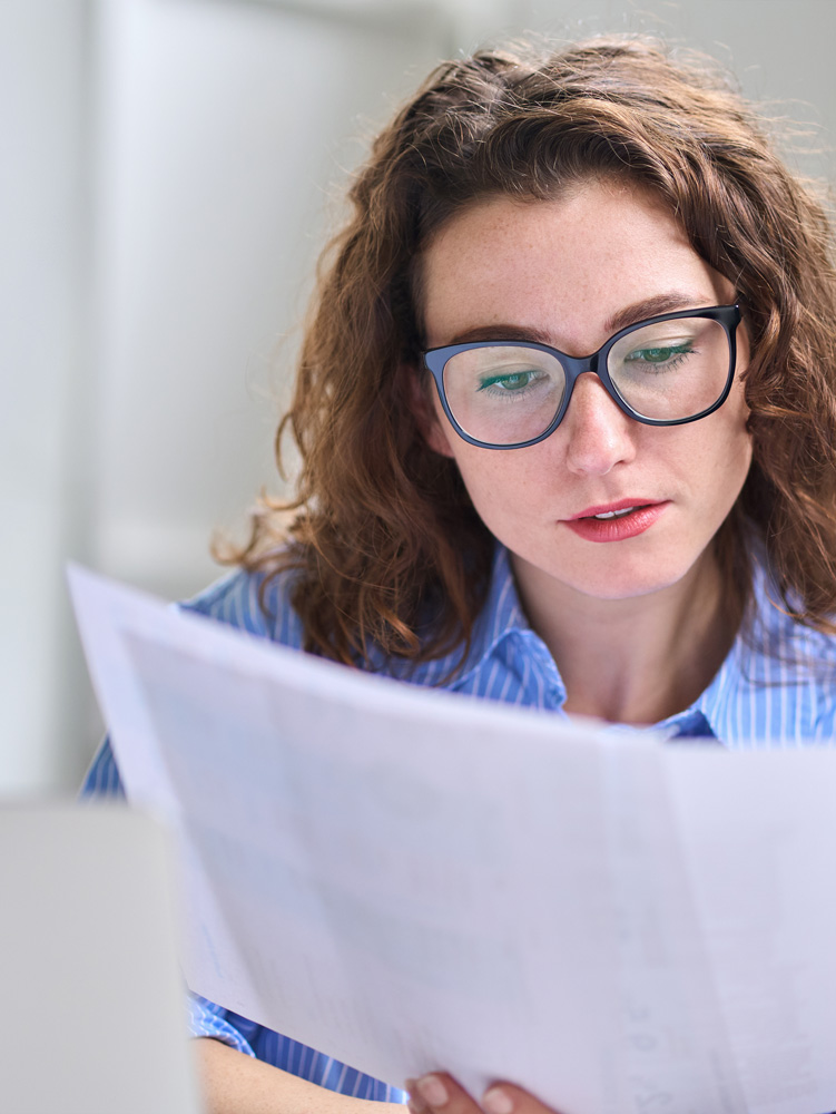 Young woman holding claim documents checking information in office