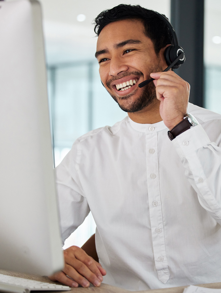 IT Support personnel with headset talking to client while looking at desktop computer screen