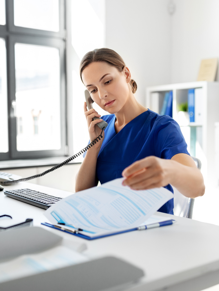 nurse with computer and clipboard calling on phone