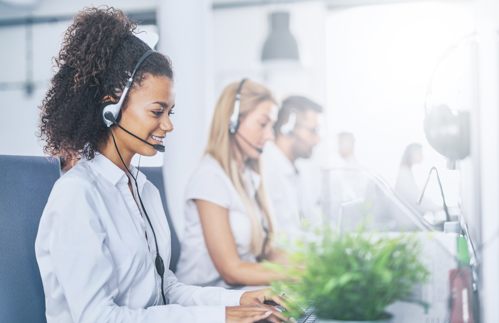Medbill worker with headset in front of her computer accompanied by her team